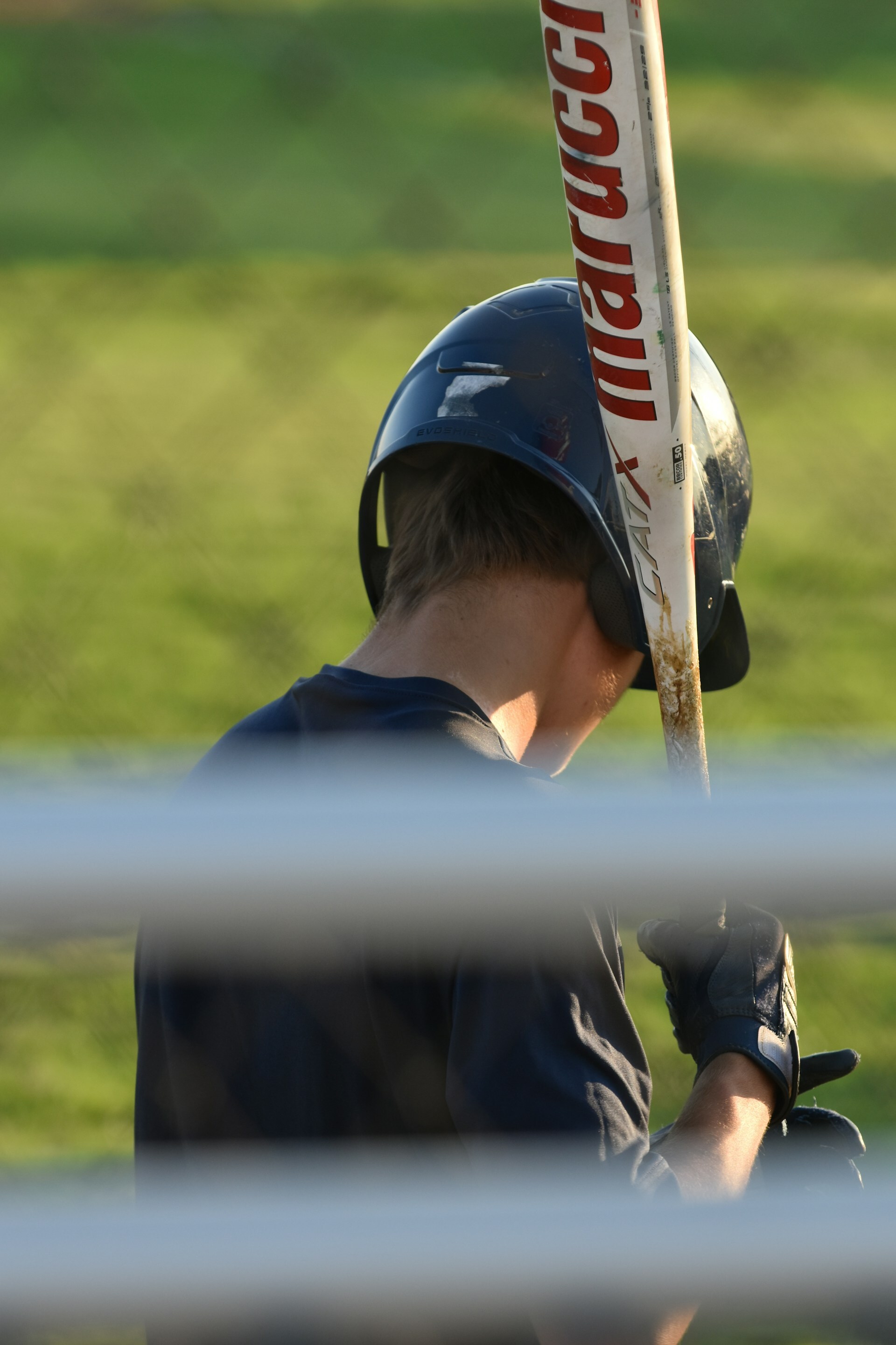 Eli Carter holding a baseball bat near the dugout